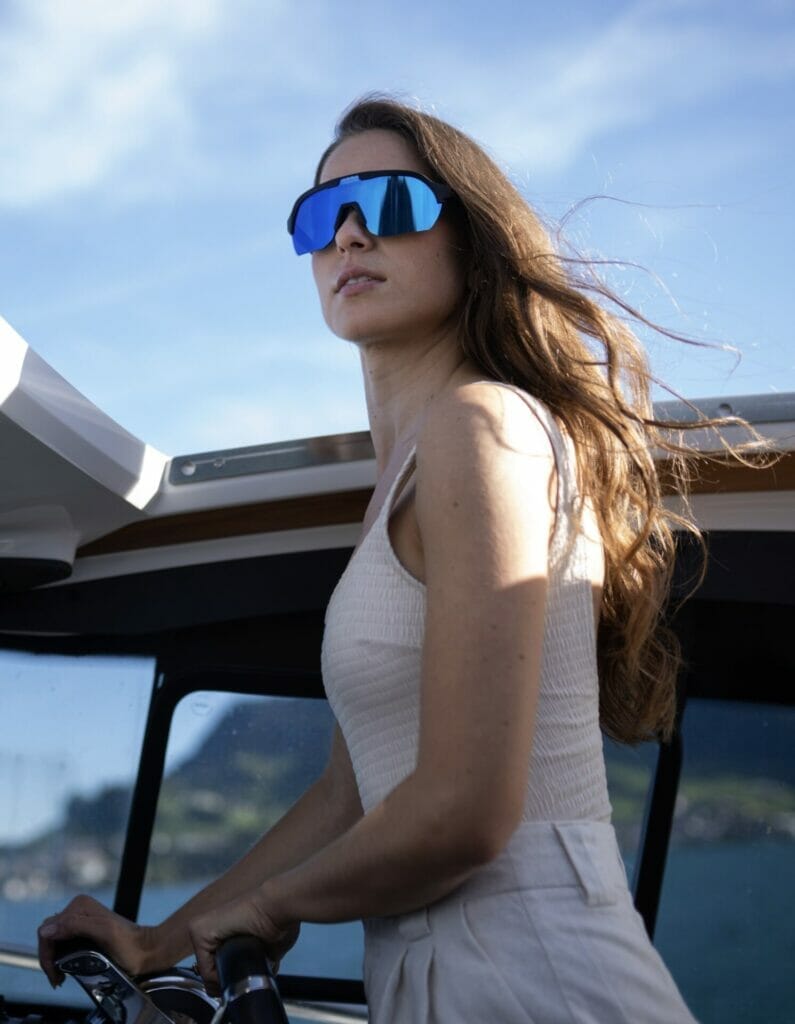 A woman driving a yacht wearing a React Sunglasses - image for React Products.