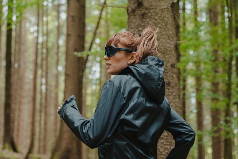 A woman wearing React Sunglasses while jogging in the woods - image for React Products.